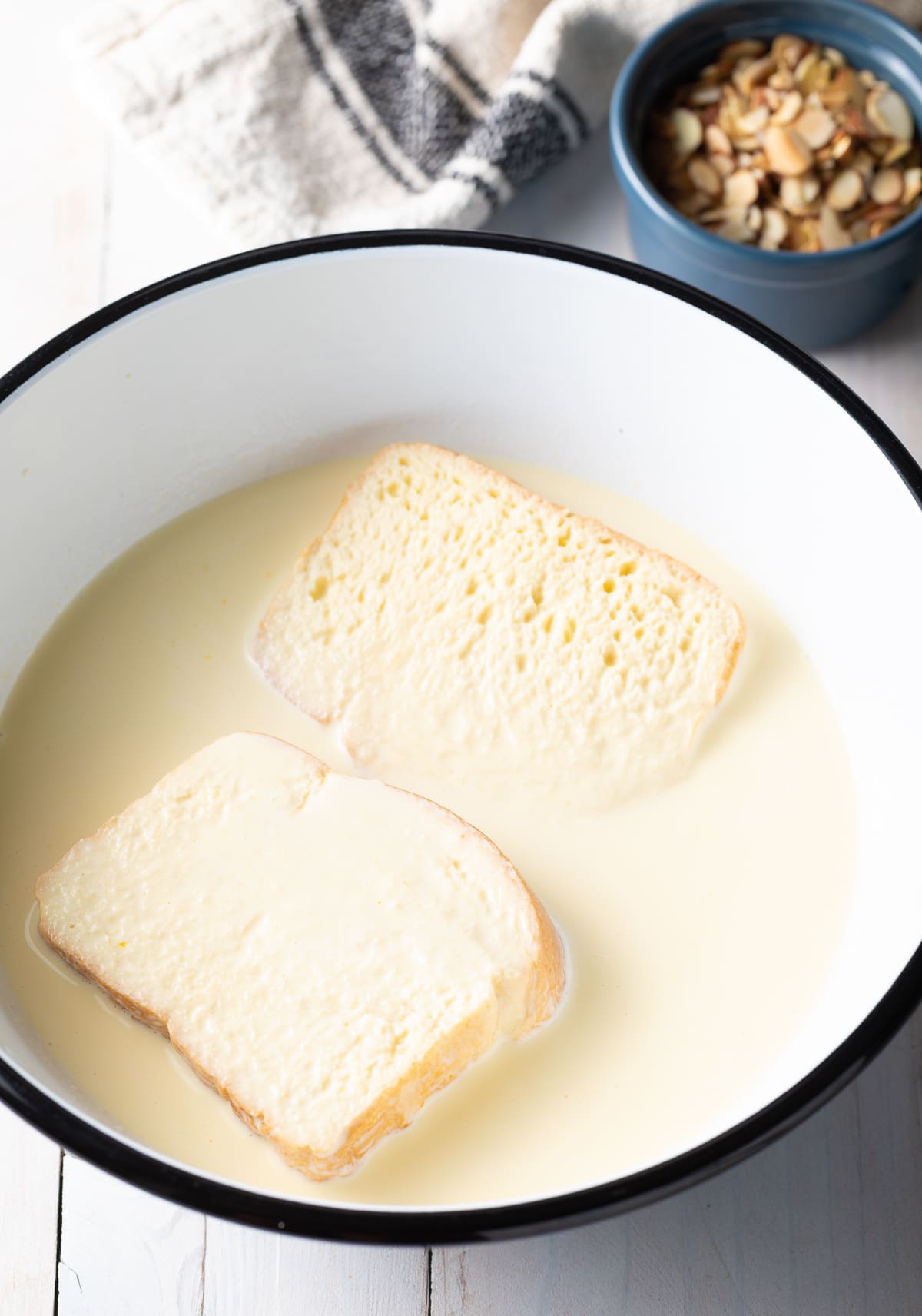 Brioche slices being soaked in egg mixture. 