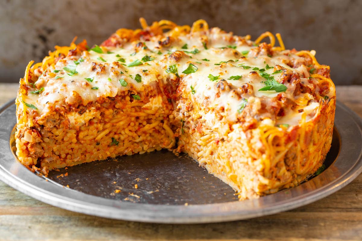 Wide shot of cooked spaghetti pie with a hefty slice removed.