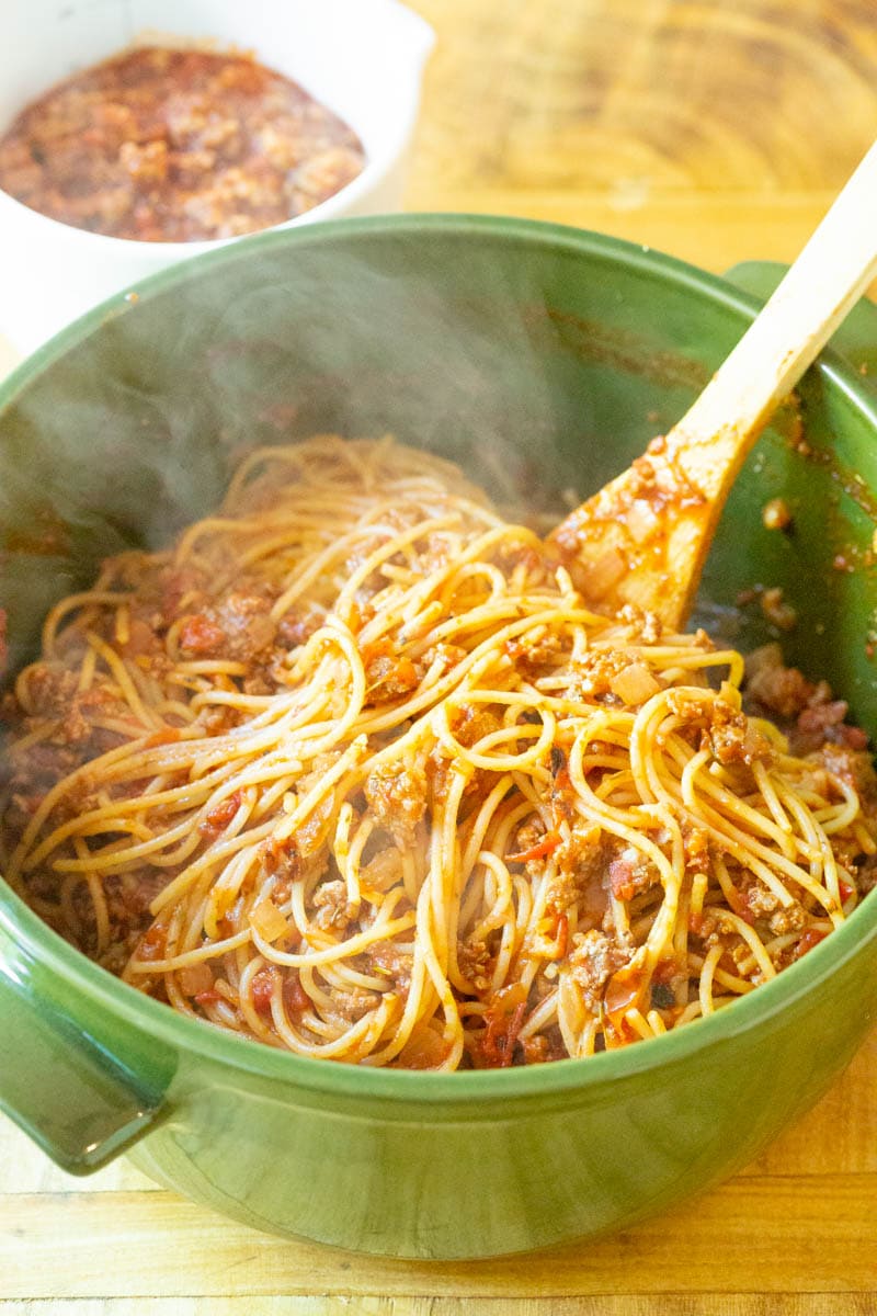Close up of spaghetti being mixed with meat sauce.