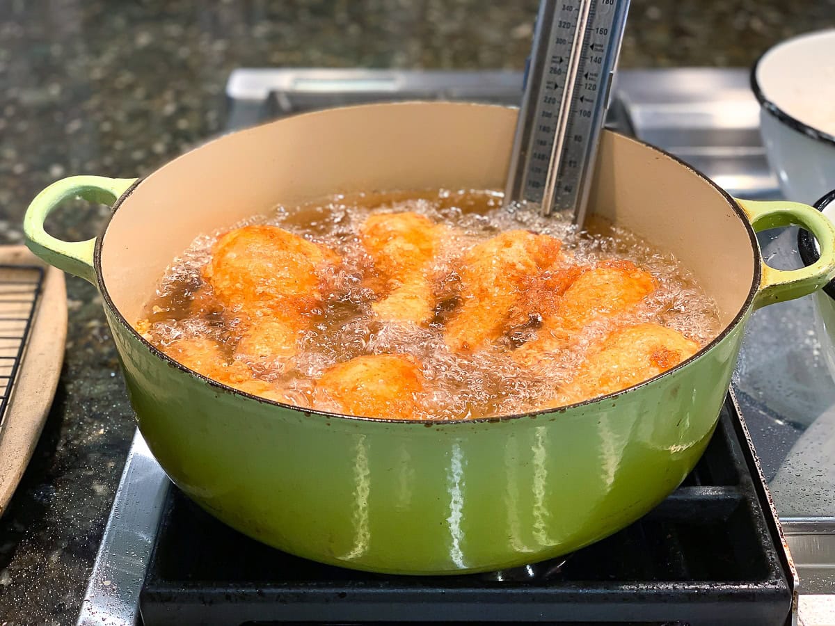 Frying chicken in a large green dutch oven.
