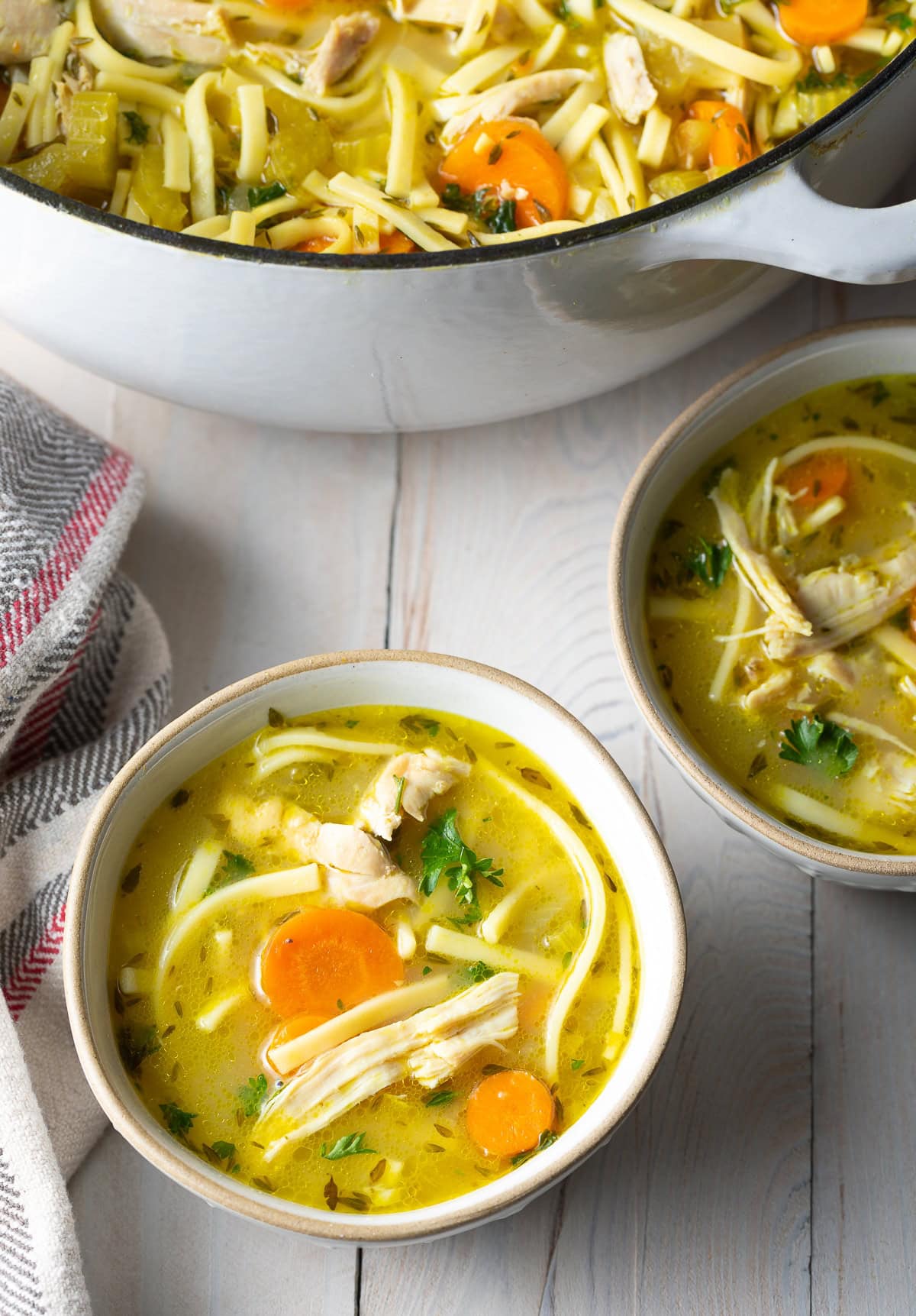 A couple servings of soup in a few bowls next to the large pot of soup.