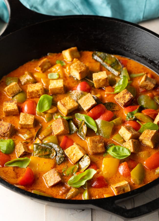 Thai Panang Curry with thickened sauce and fresh Thai basil leaves in a large cask iron skillet.