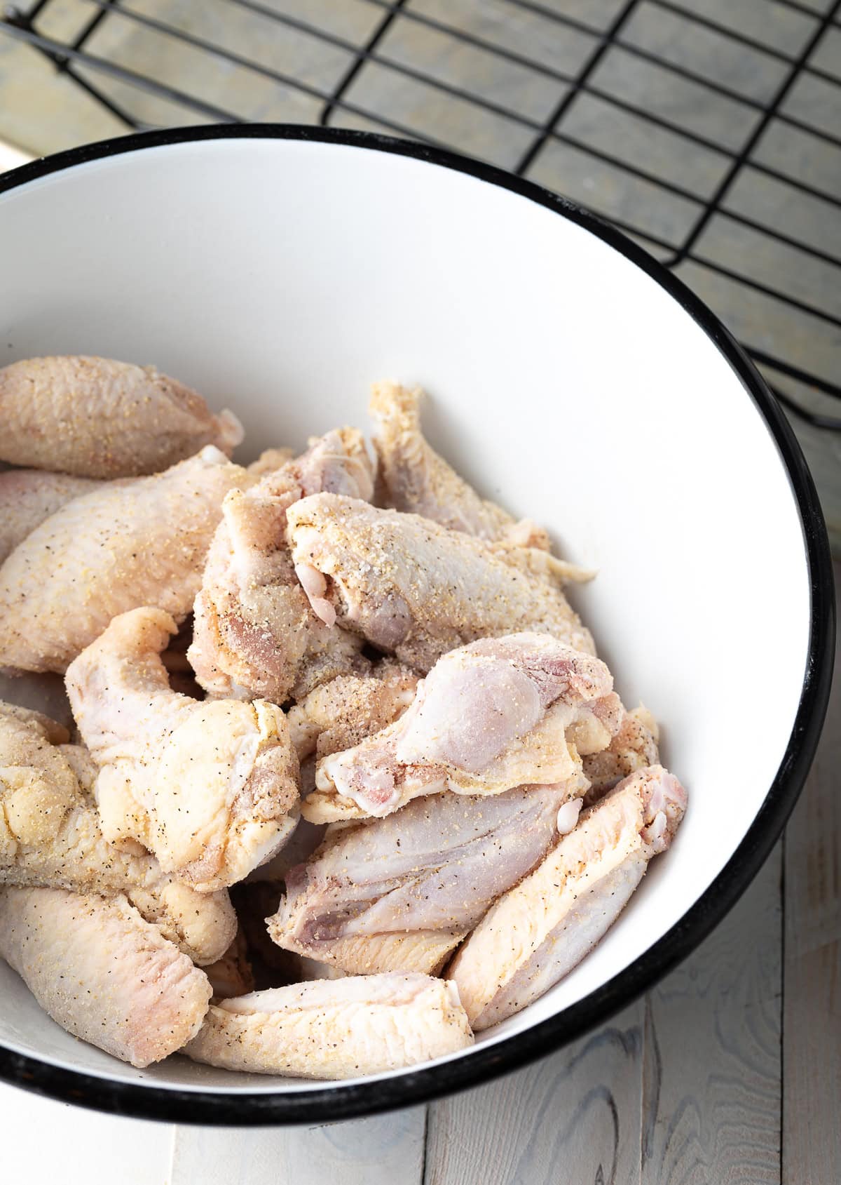 Raw chicken wings in a white mixing bowl.