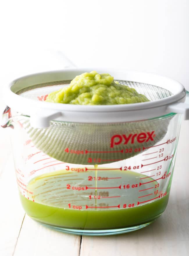 Celery pulp being strained into a small glass container.