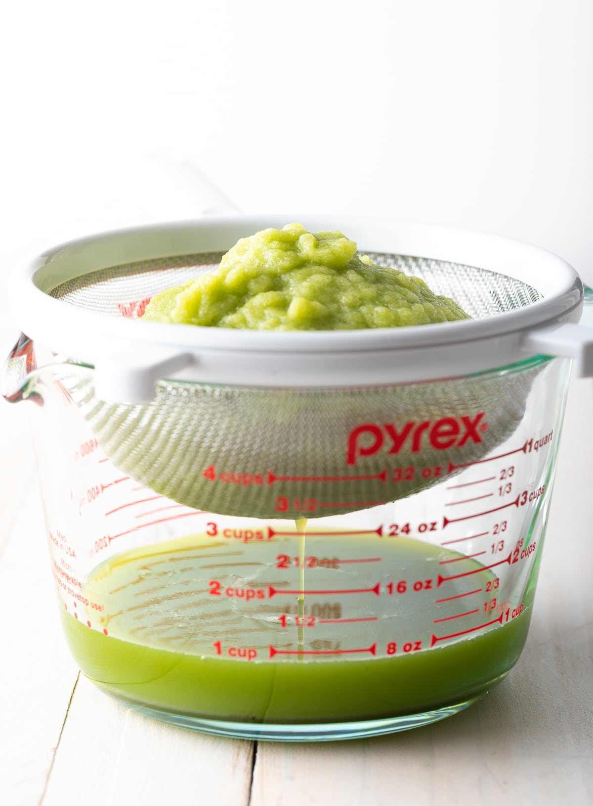 Celery juice being drained into a glass.
