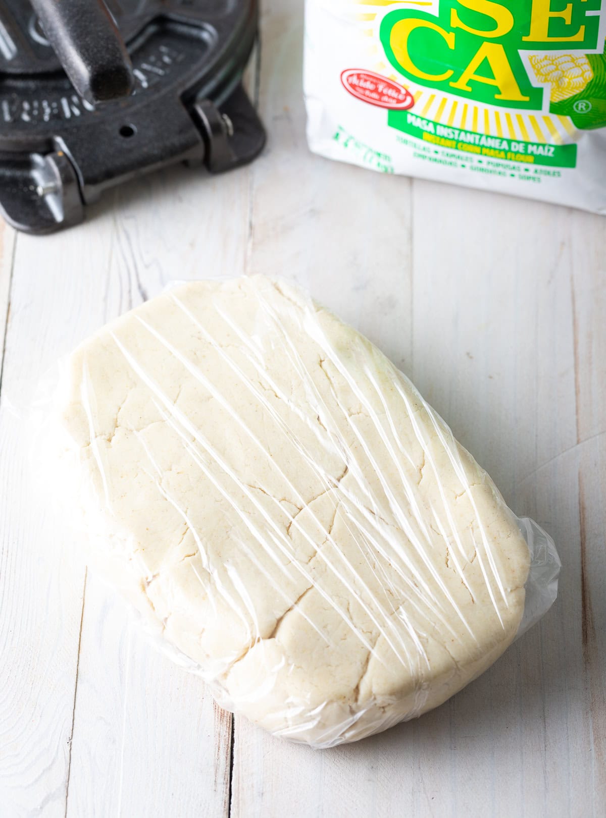 Rectangular dough shape wrapped in plastic resting on a countertop. 