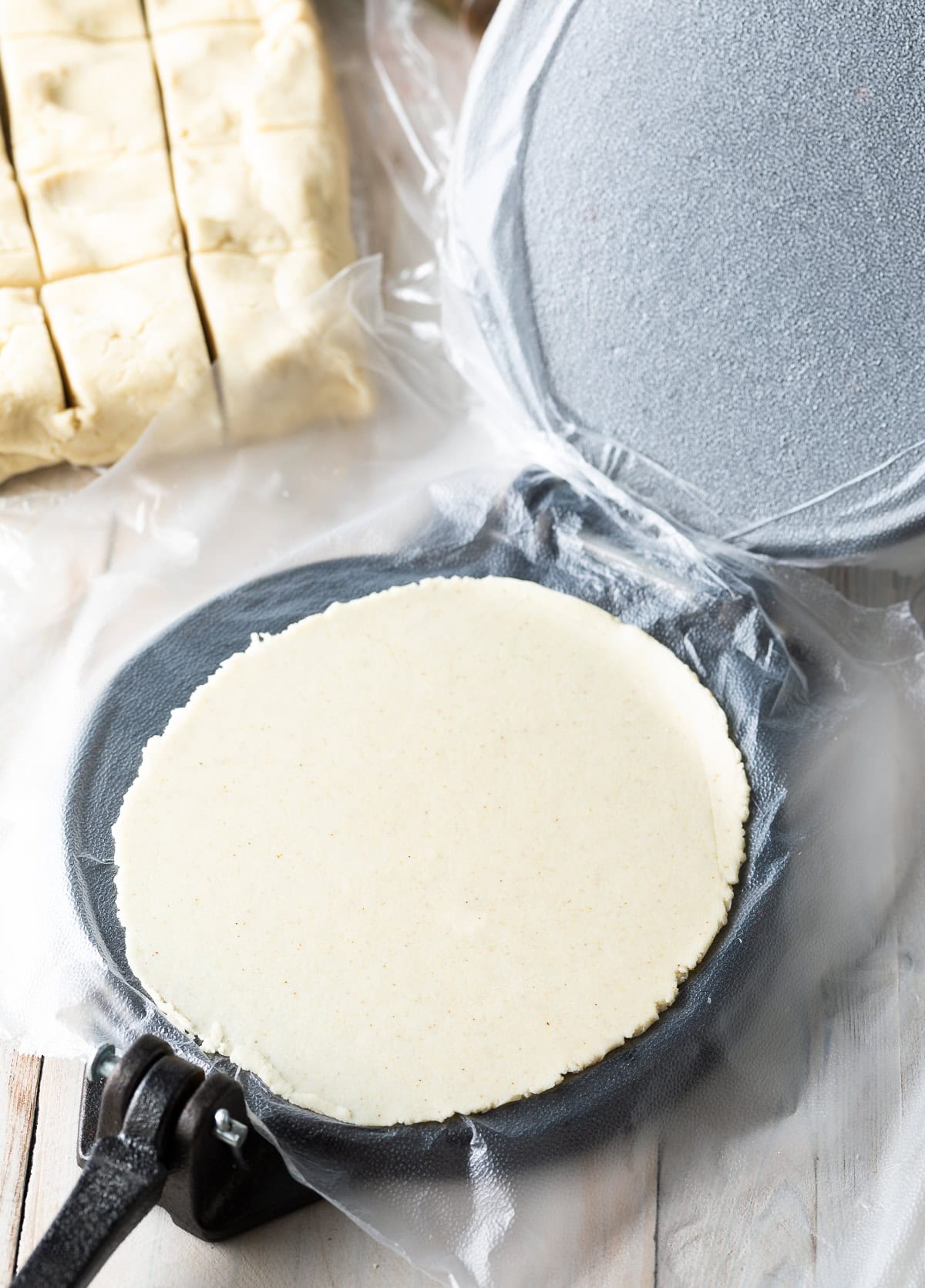 Flattened corn tortilla in the tortilla press/ 