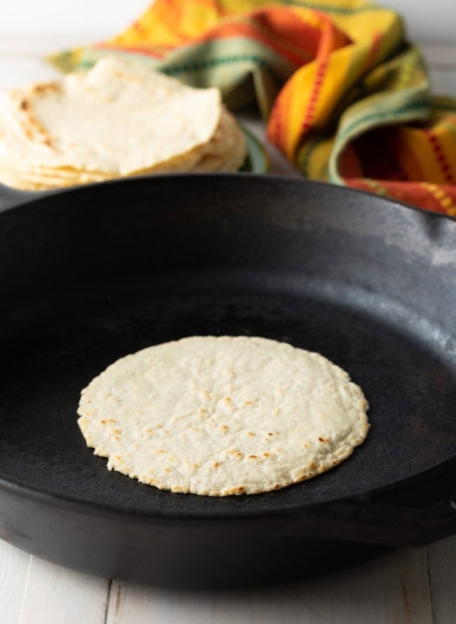 Corn tortilla being cooked on a skillet. 