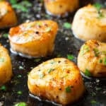 Seared scallops with garlic and herbs, cooked to perfection and served on a sizzling skillet.