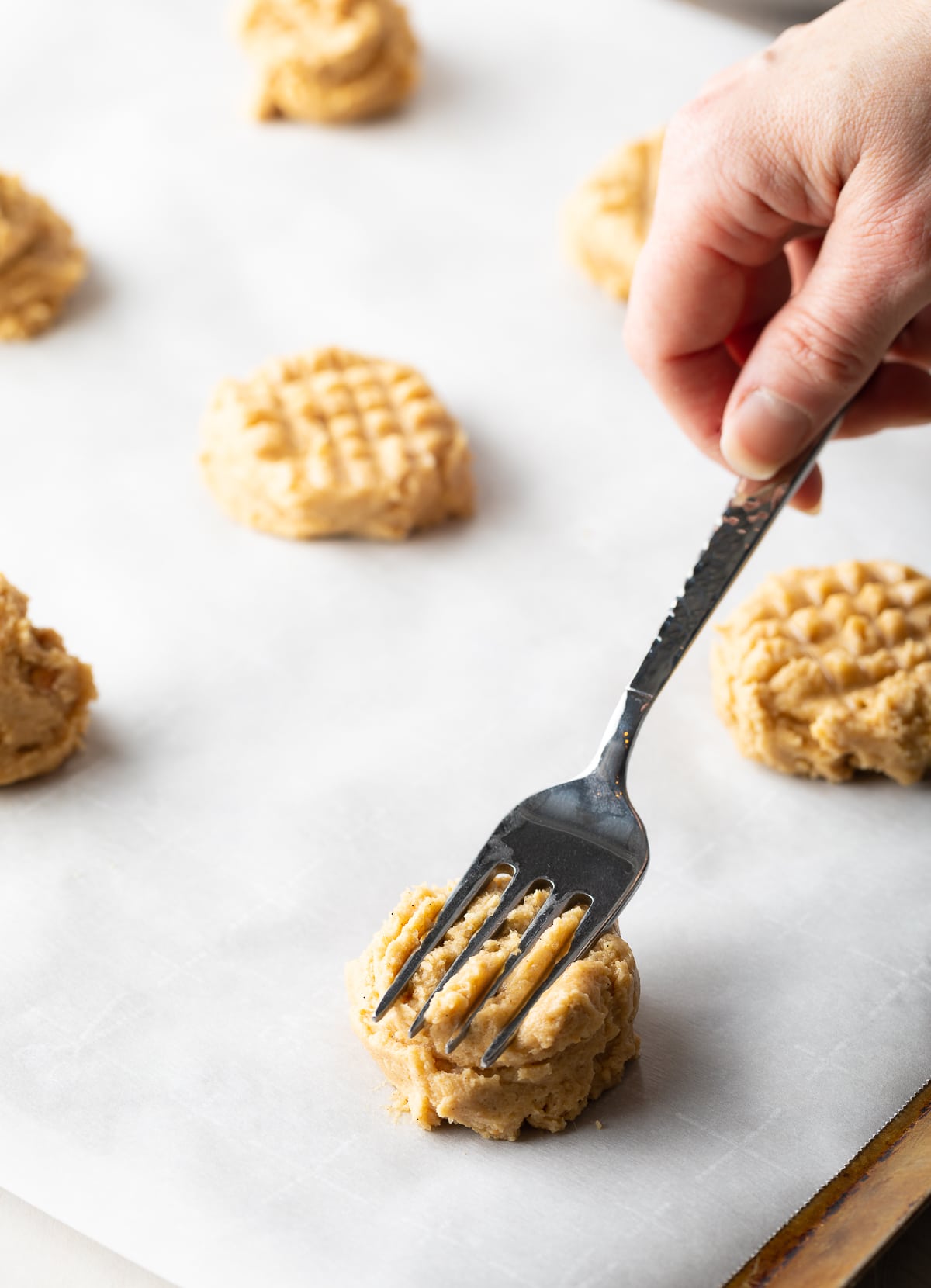 Pressing Best Peanut Butter Cookie Recipe dough balls with fork to create a pattern on top