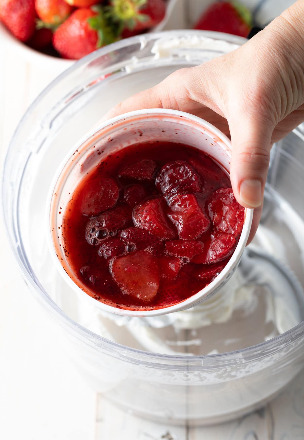 Hand holding strawberries to camera. 