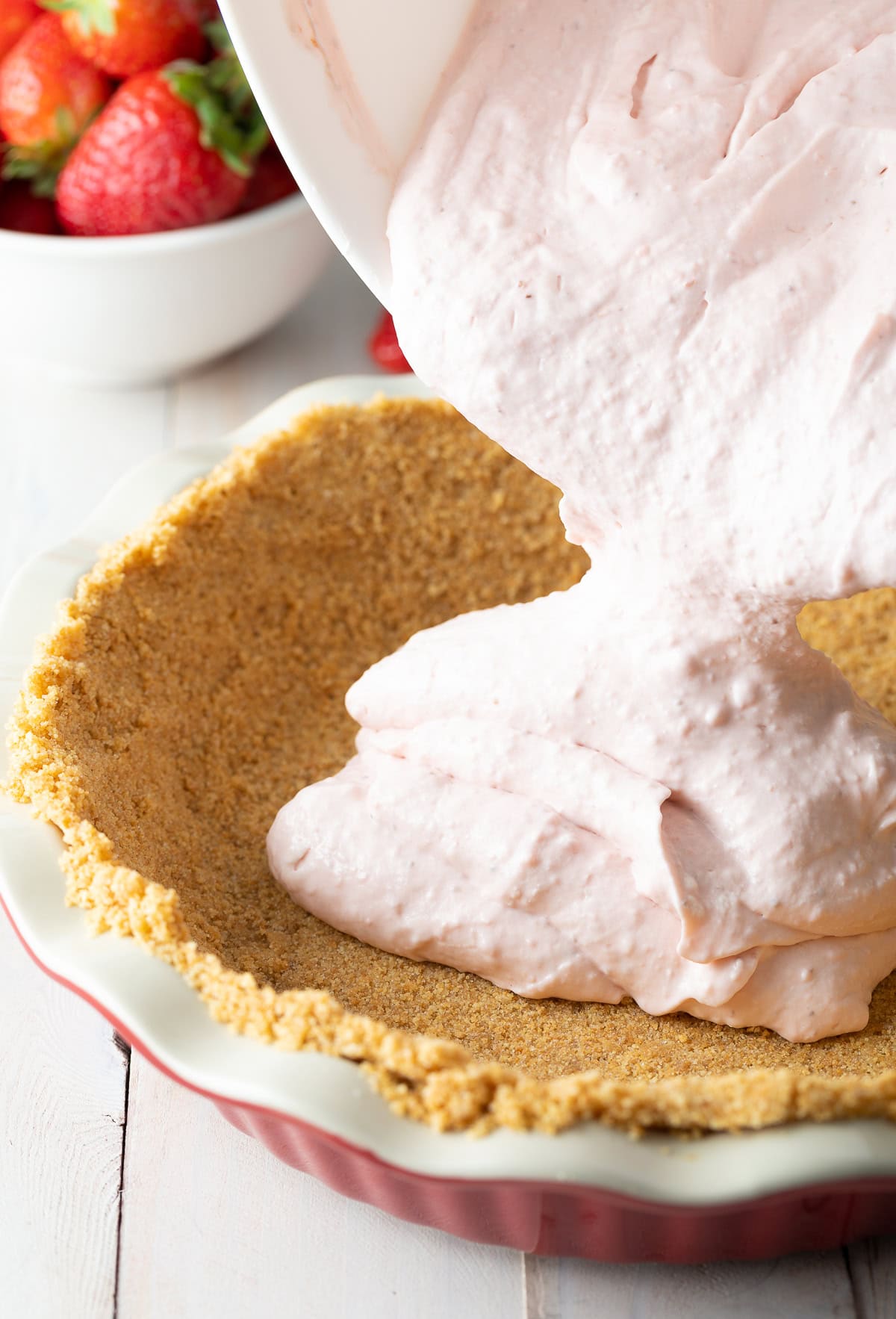 Filling being poured onto the graham cracker crust. 