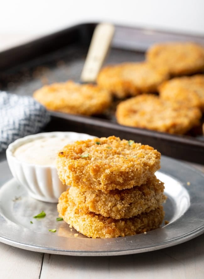 Stacked baked green tomatoes on a plate.