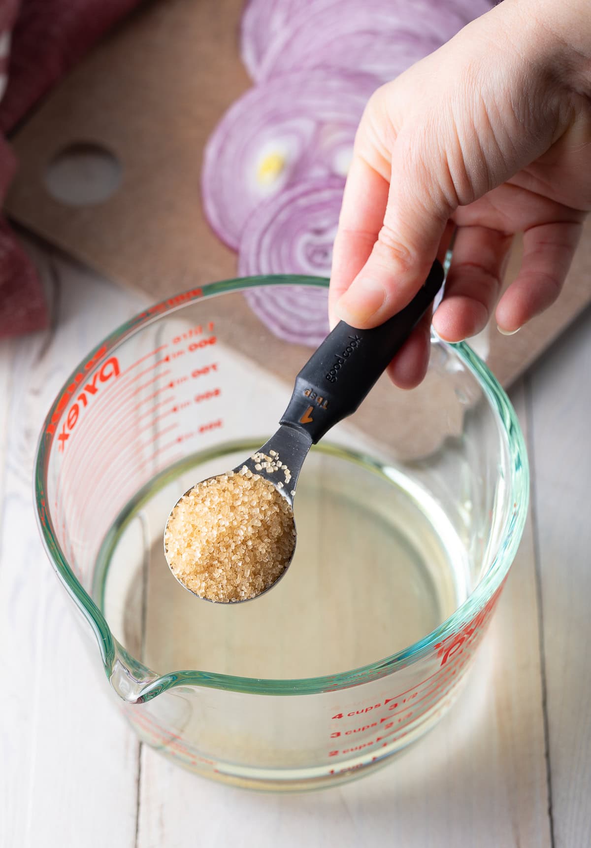 Jar filled with water and hand adding sugar.