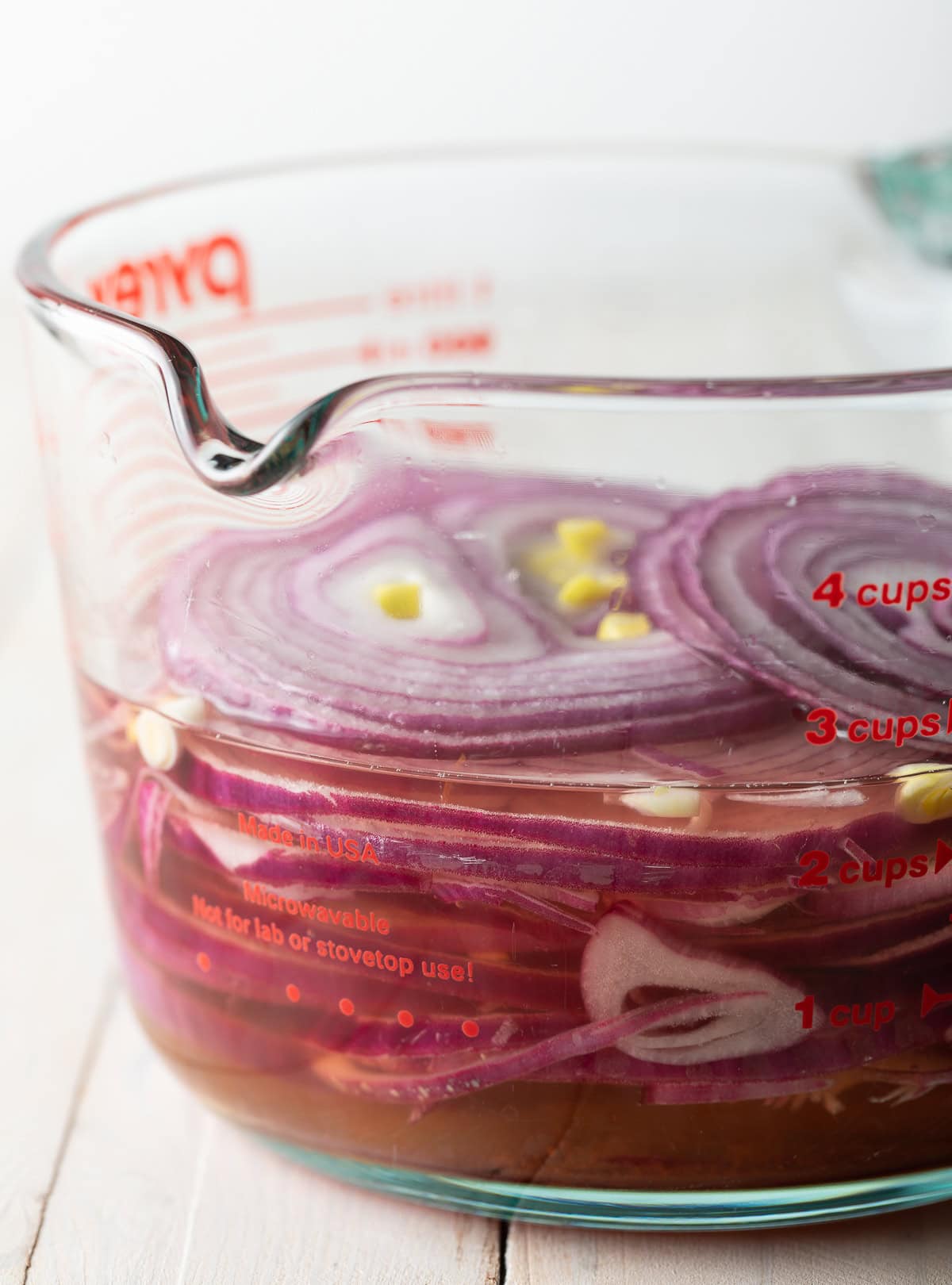 Red onions submerged in pickling juice.