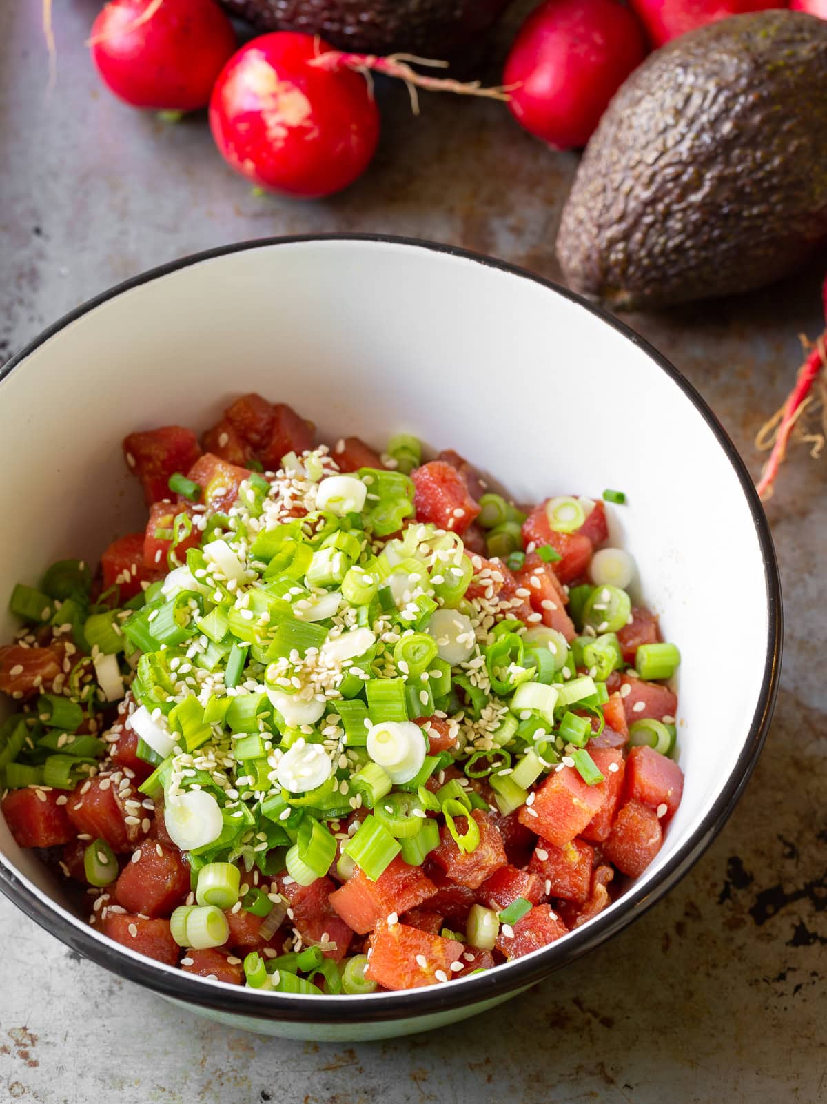 Bowl of ahi tuna poke topped with chopped green onion.