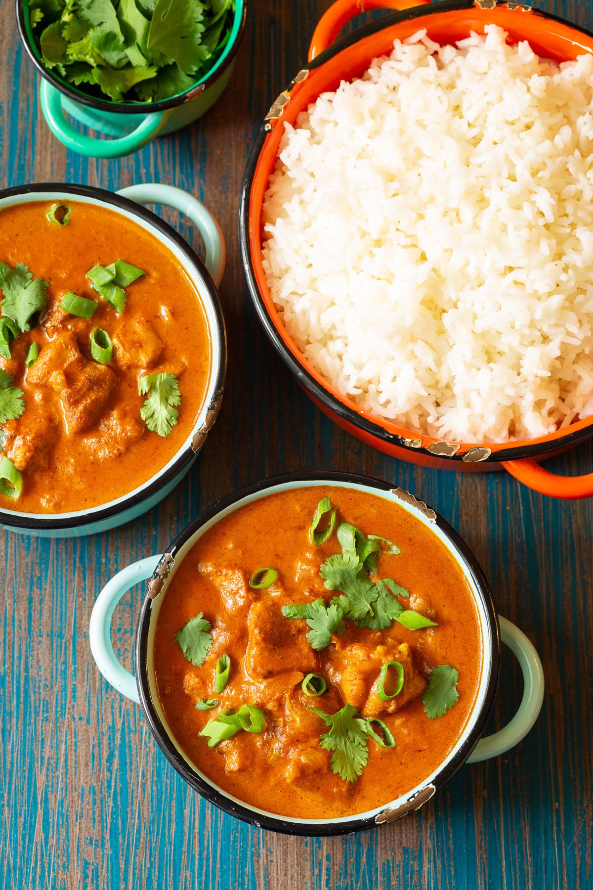 Top down view of bowls filled with ready to serve chicken curry and side of rice. 