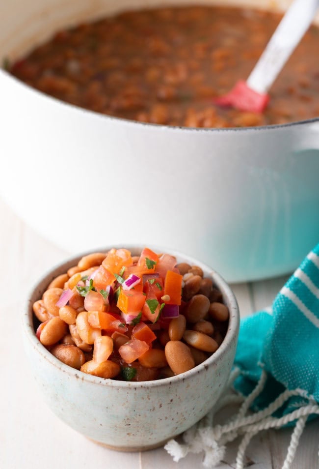 Closeup of a small bowl of pinto beans topped with pico de gallo.