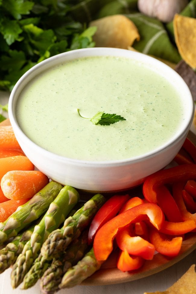 Closeup of plated chimichurri in a bowl served with sliced fresh veggies.
