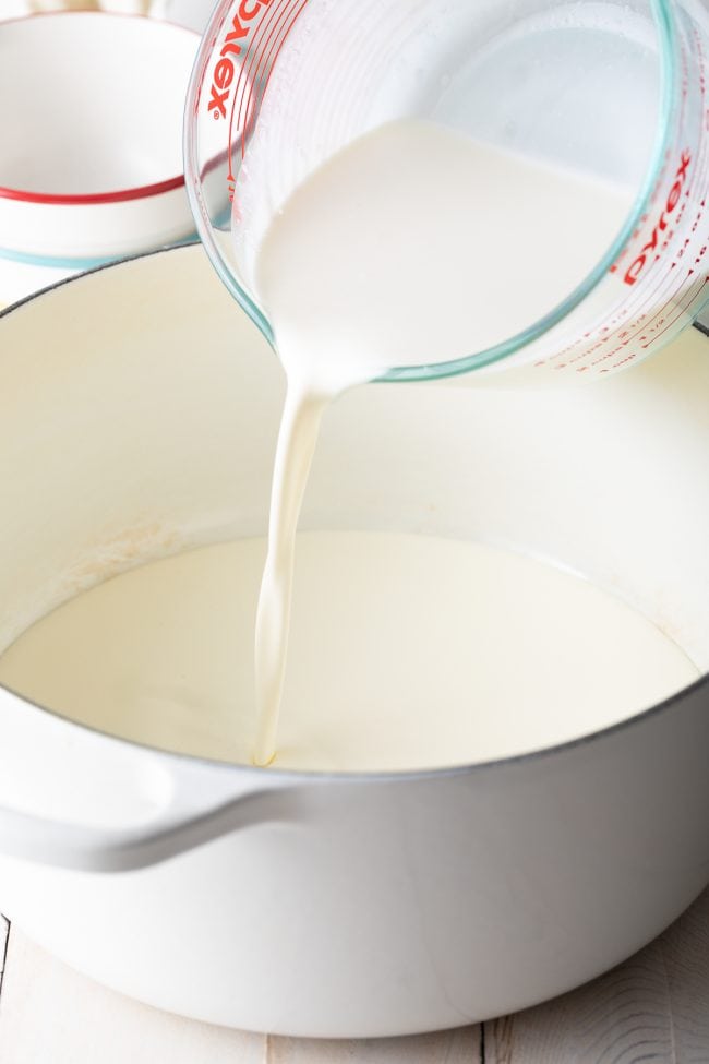 Cream and milk being poured into pot.