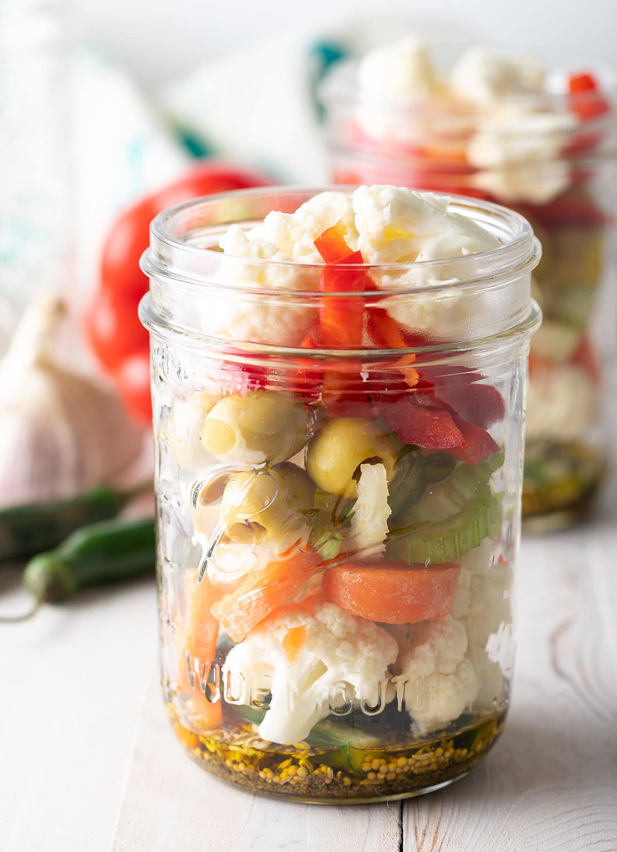 A jar filled up with spices and chopped veggies. 