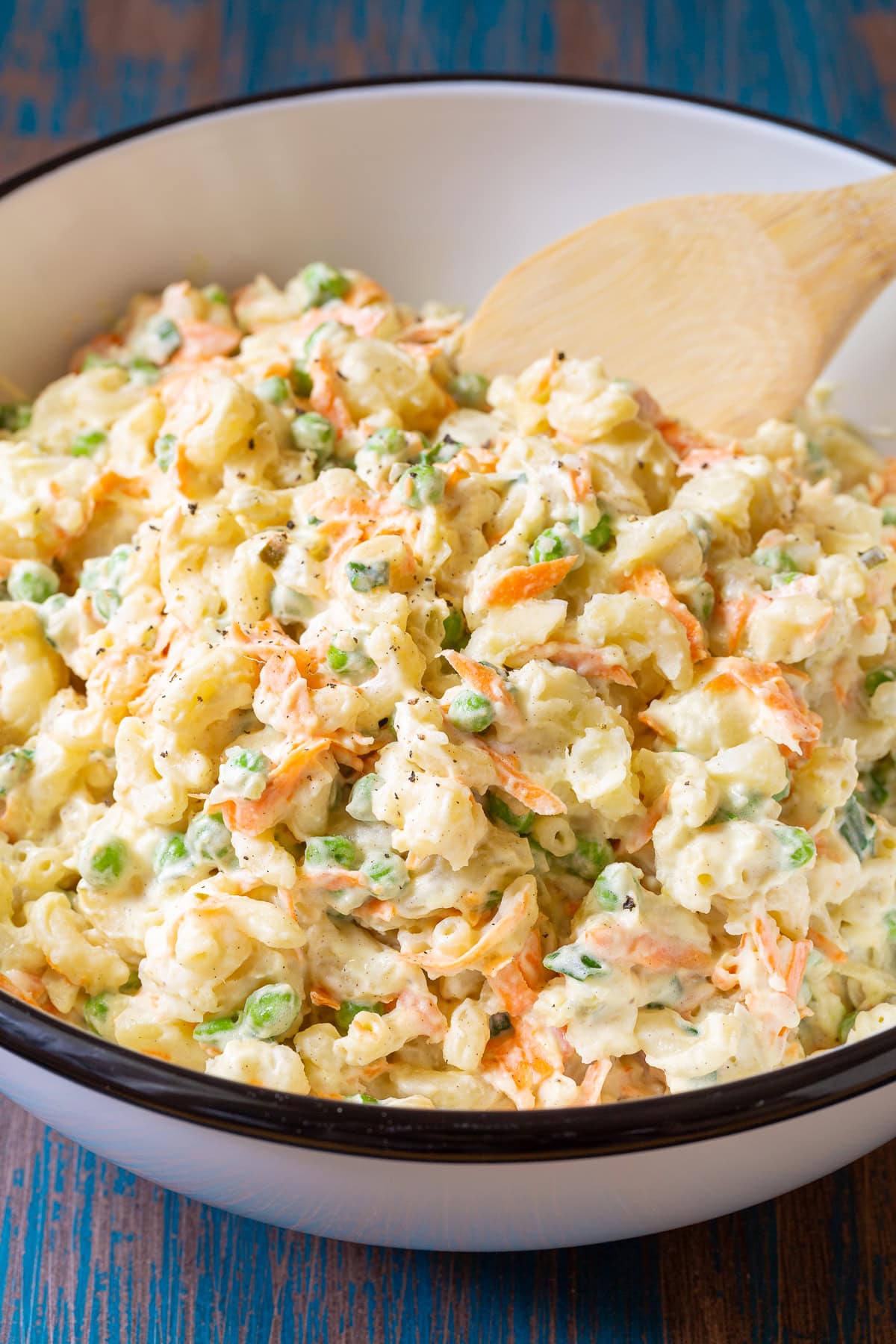 Bowl of potato and mac salad with a wooden spoon. 