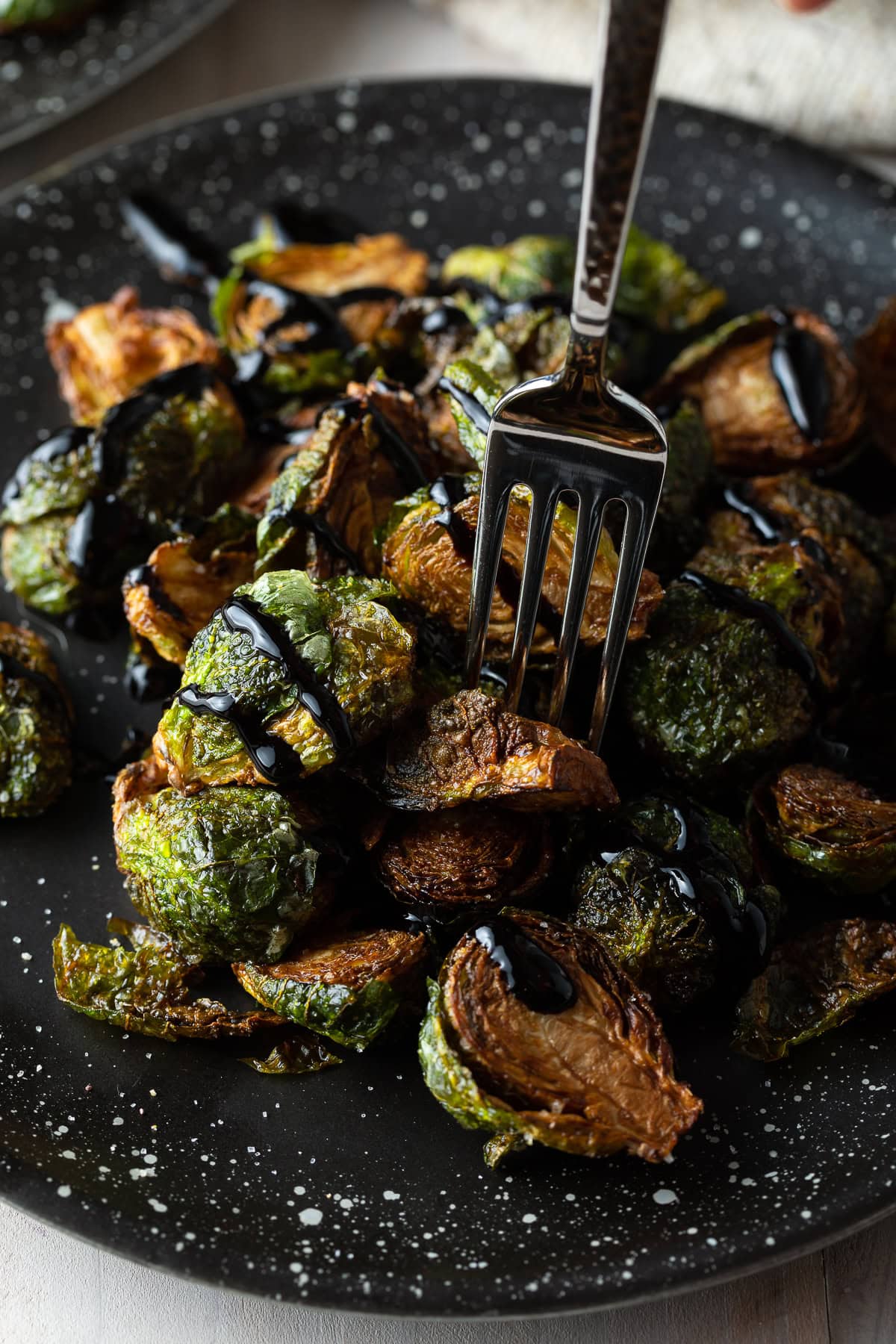 Fork piercing sprouts drizzled with glaze. 