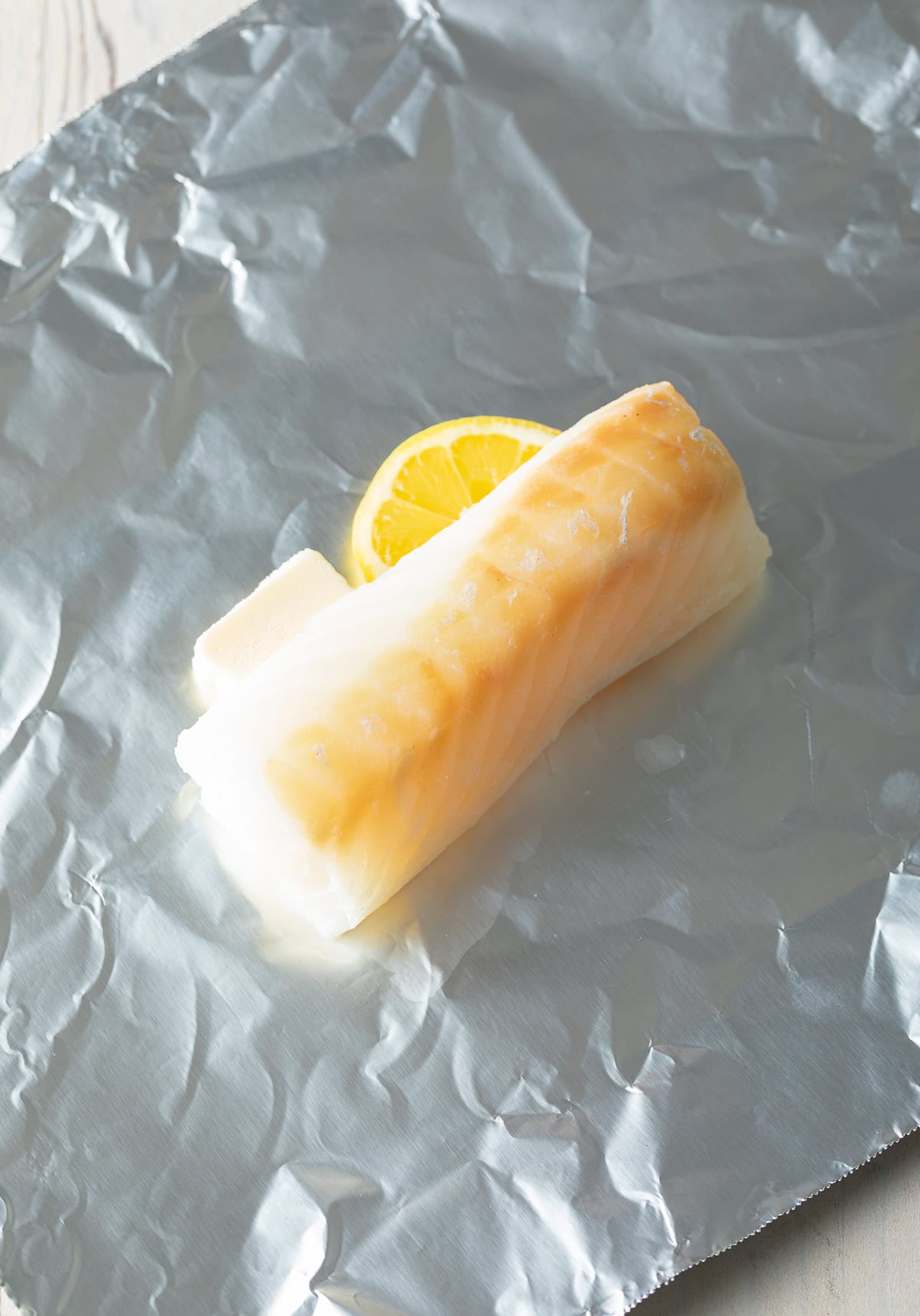 Foil topped with butter, lemon and patted fish fillet. 