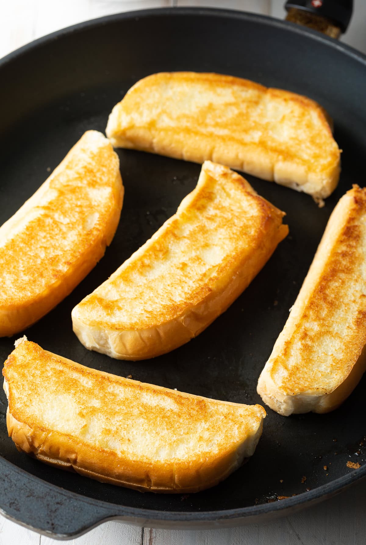 Buns lathered in butter being toasted in skillet. 