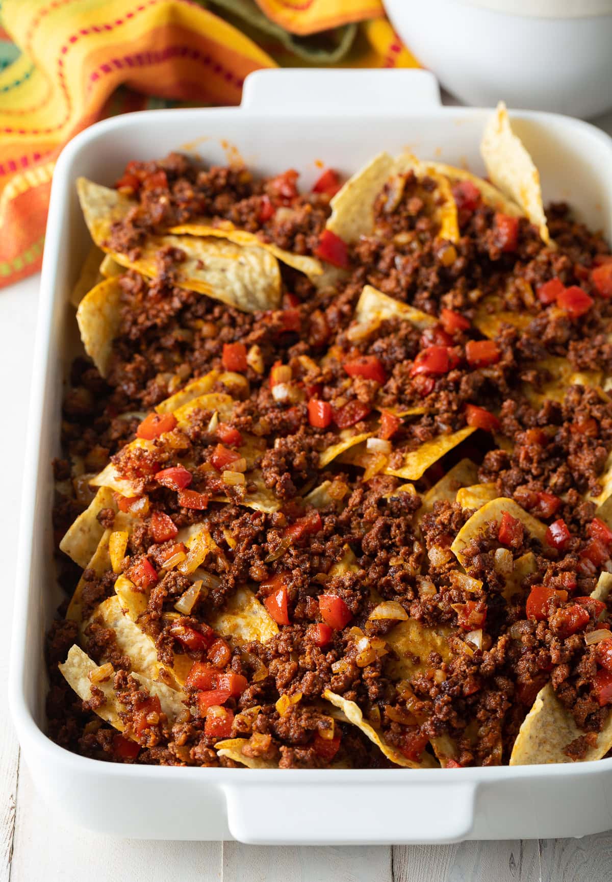 Baking dish filled with tortilla chips and topped with chorizo mixture. 
