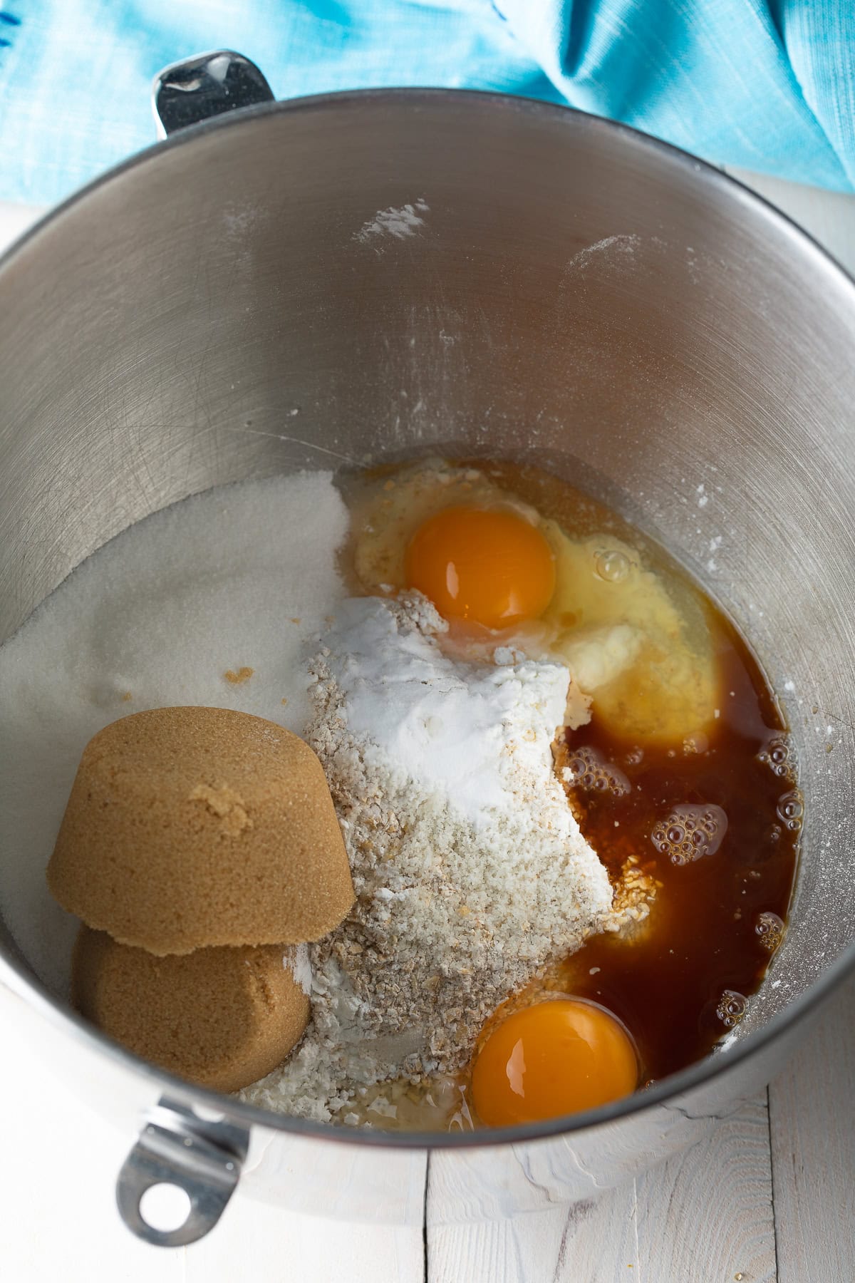 Metal mixing bowl with brown sugar and white sugar, flour, eggs, and vanilla.