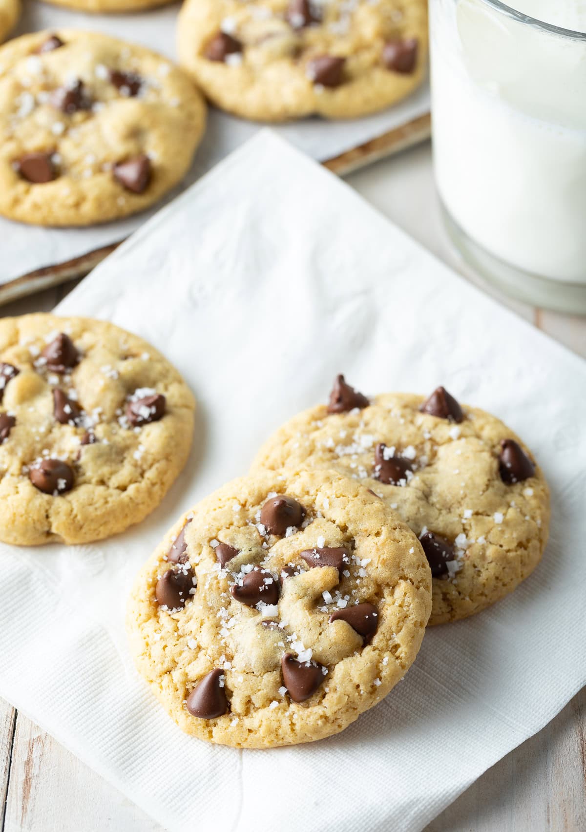Three chocolate chips cookies on a white napkin.