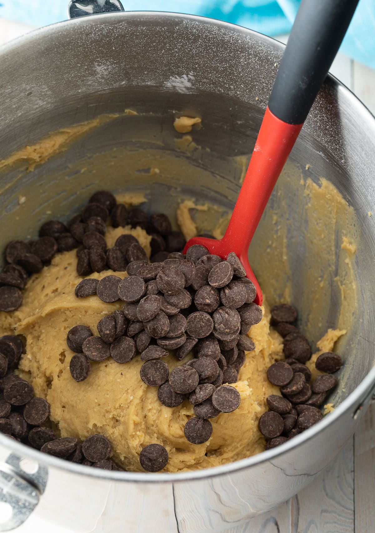 Using a red spatula to stir chocolate chips into cookie dough.