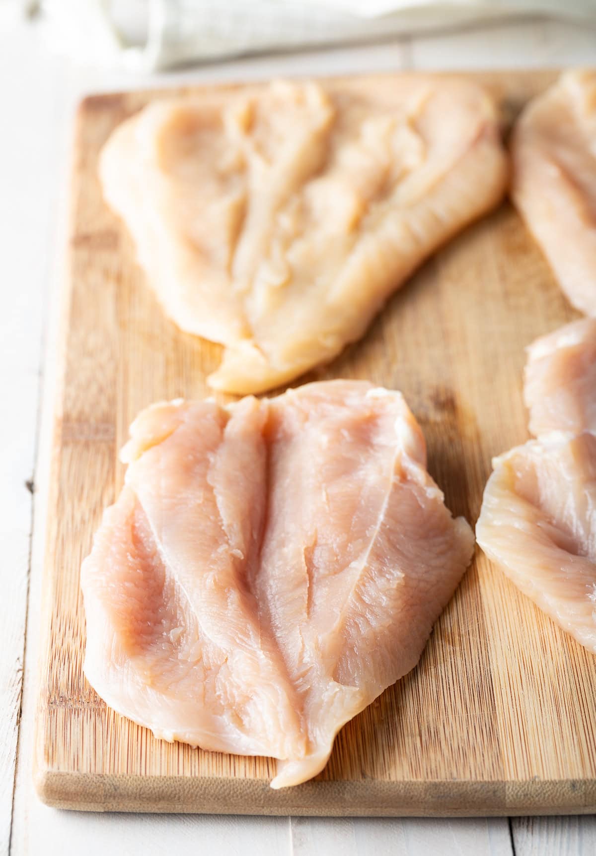 Butterflied chicken breasts on a wood cutting board.