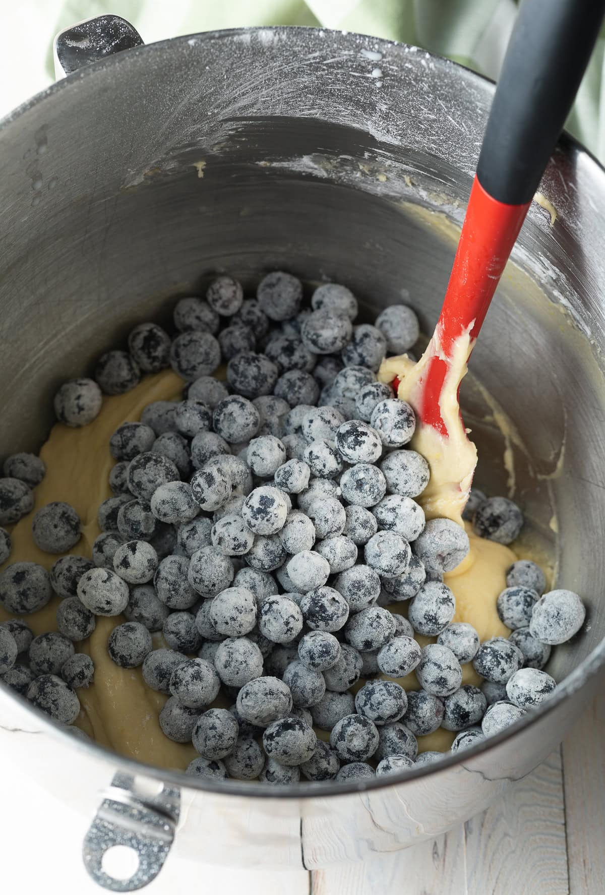 Blueberries are being added to a blueberry muffin recipe mixture.