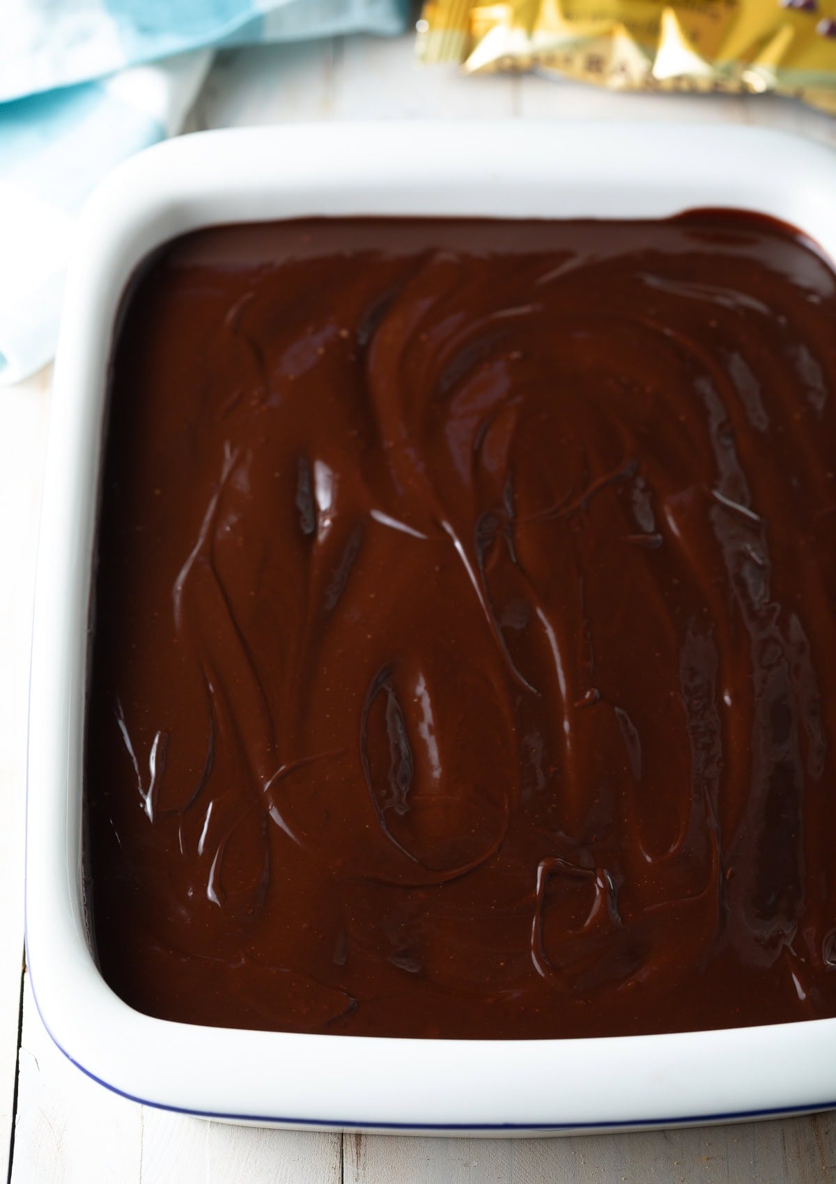 Top down view of eclair cake in a baking dish topped with ganache.