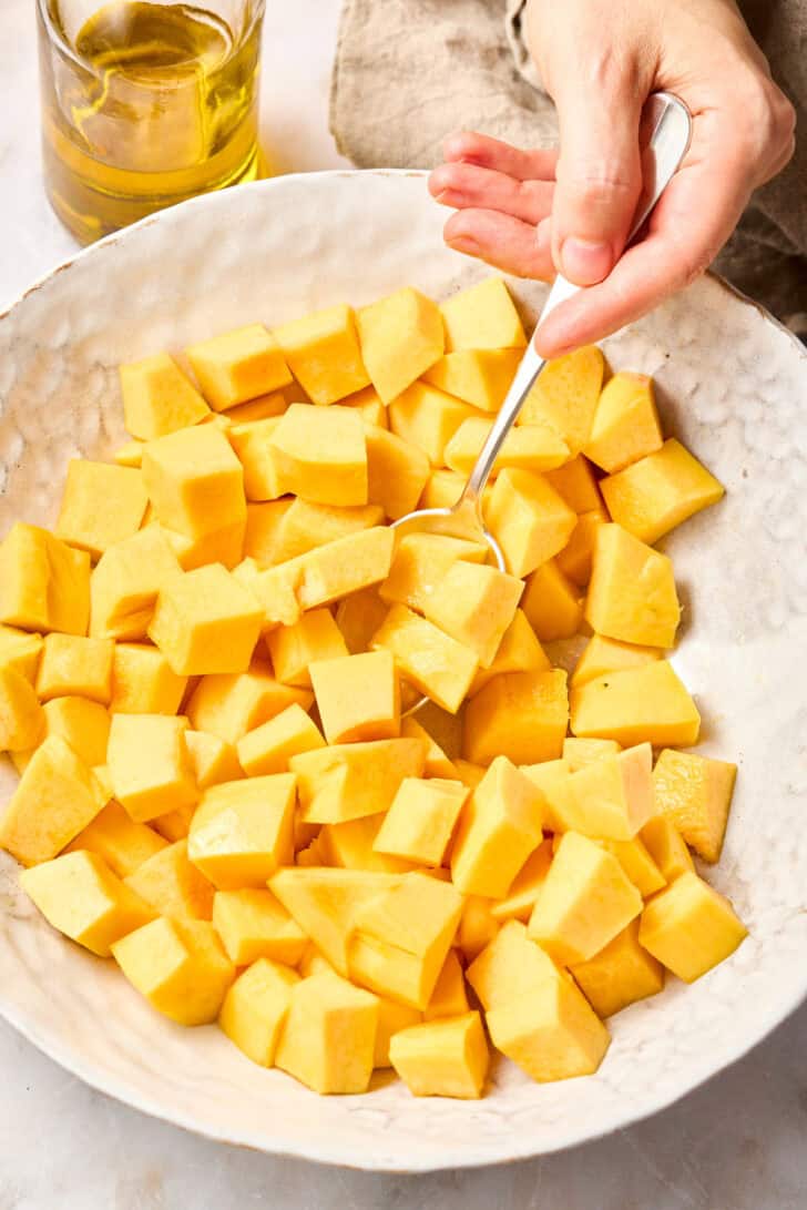 chopped butternut squash in bowl with oil