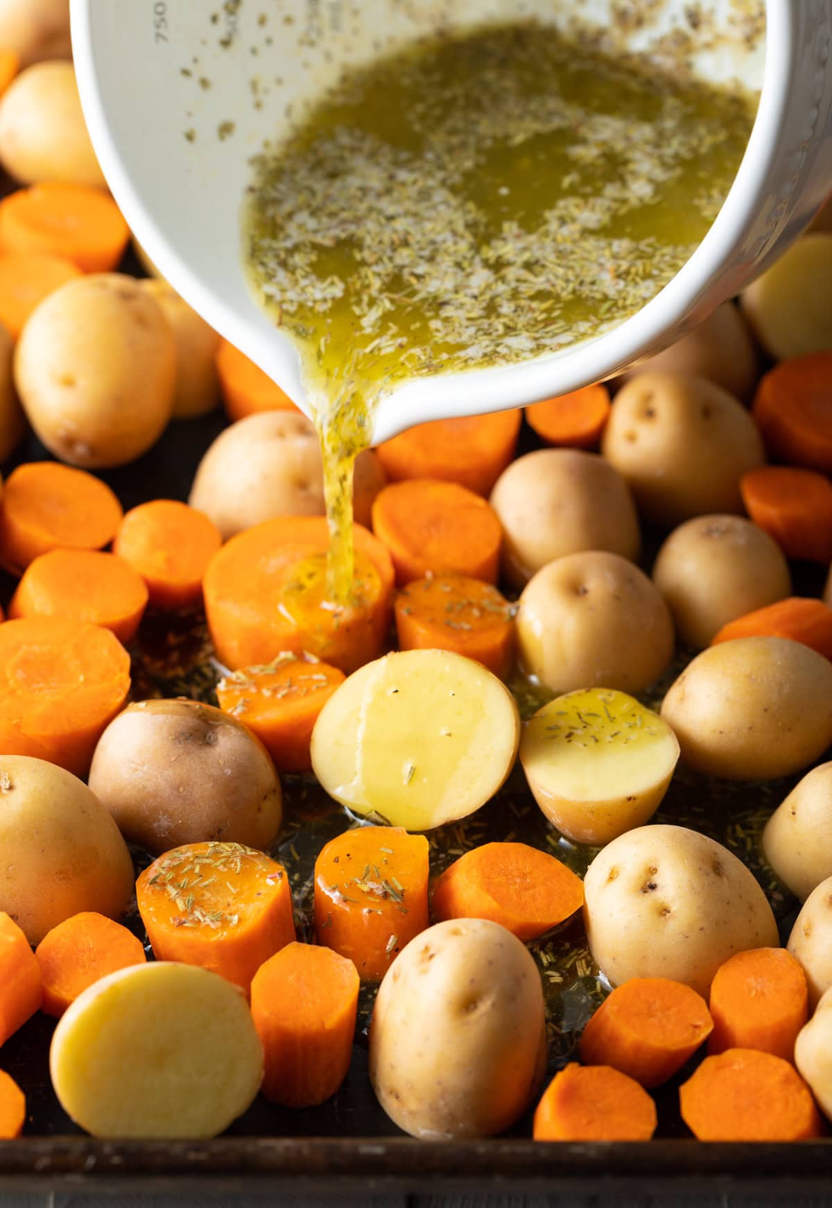 Oil and seasoning being poured over veggies.