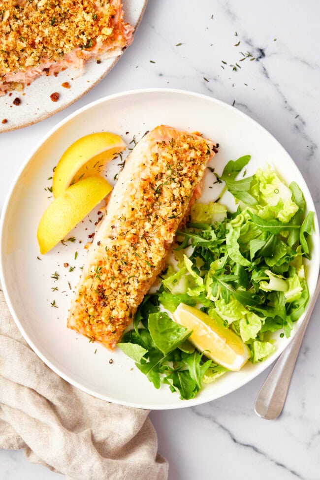 Salmon Recipe #ASpicyPerspective #Salmon #BakedSalmon #OvenBakedSalmon #SalmonRecipe #BakedSalmonRecipe #OvenBakedSalmonRecipe #HowtoBakeSalmon #ParmesanCrust #Fish #Dinner #MainDish Oven baked salmon with a parmesan herb crust on a baking sheet with a spatula on the side.