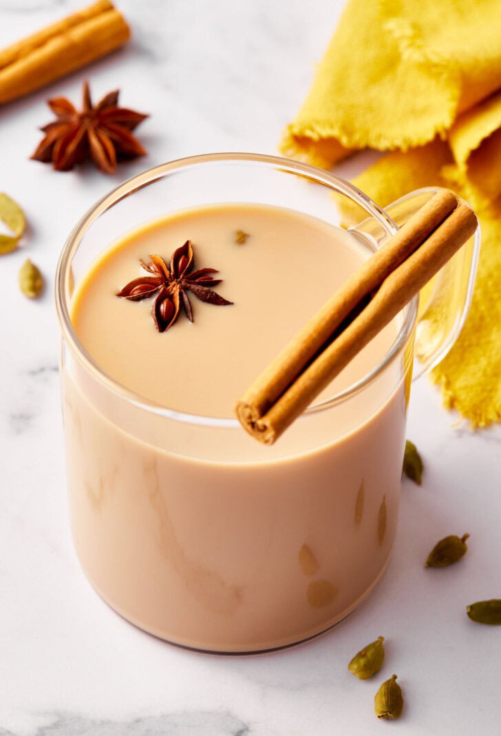 Closeup of chat tea in a glass mug garnished with a cinnamon stick.
