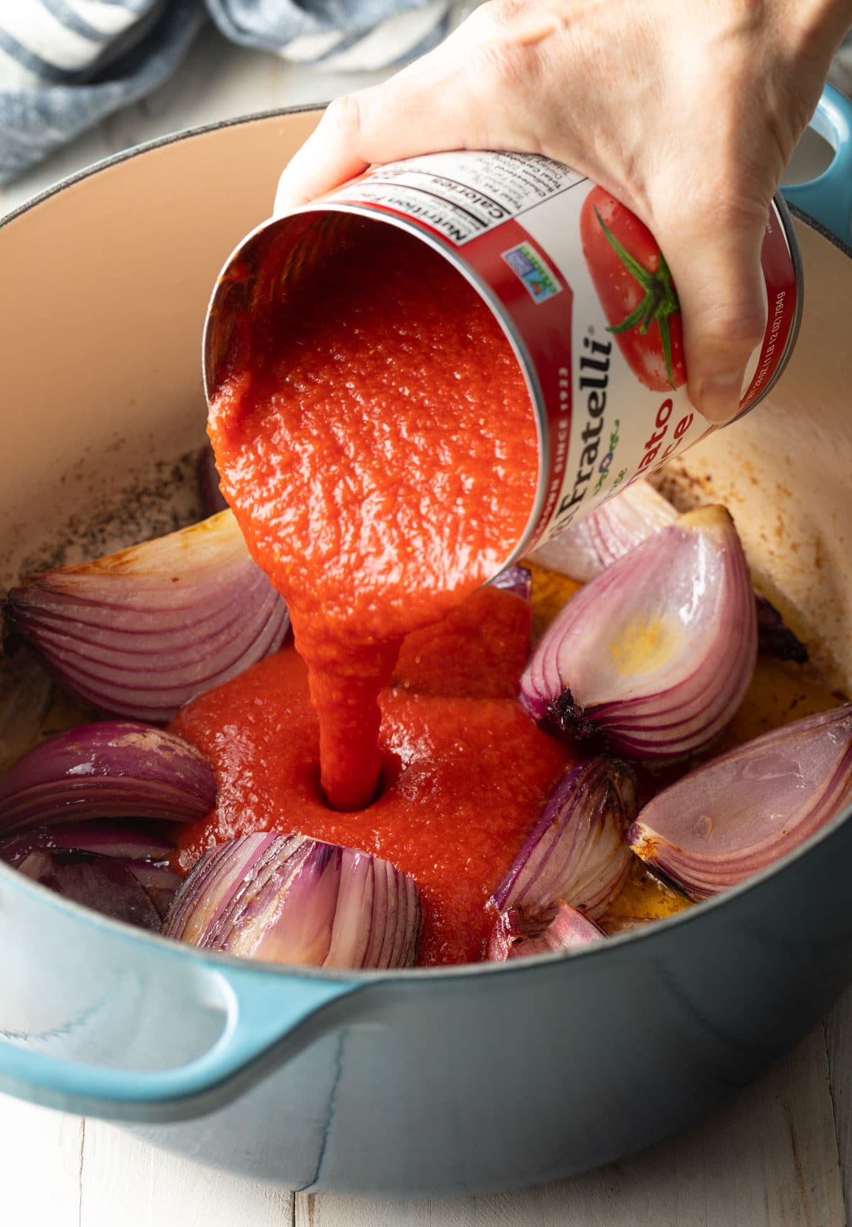 tomato sauce and onions in blue pot for the Italian sausage meatballs