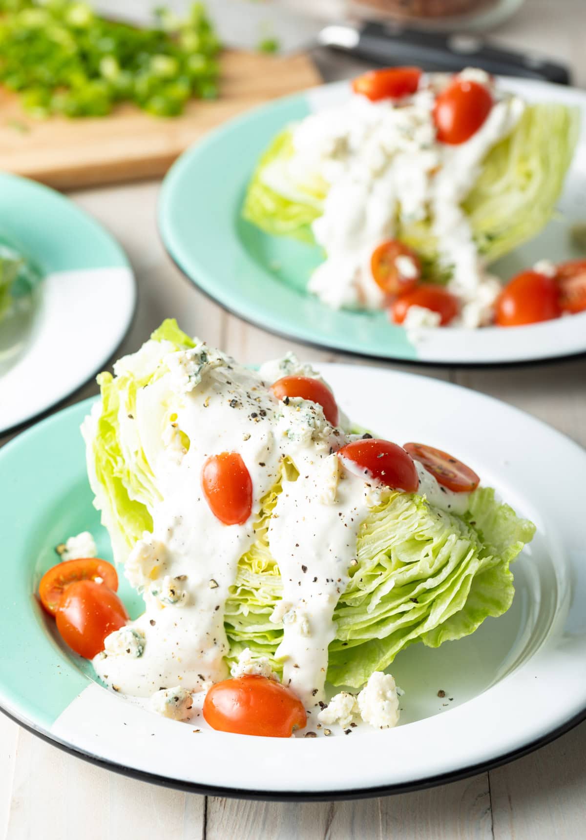 Iceberg lettuce on a plate with blue cheese dressing and halved grape tomatoes.