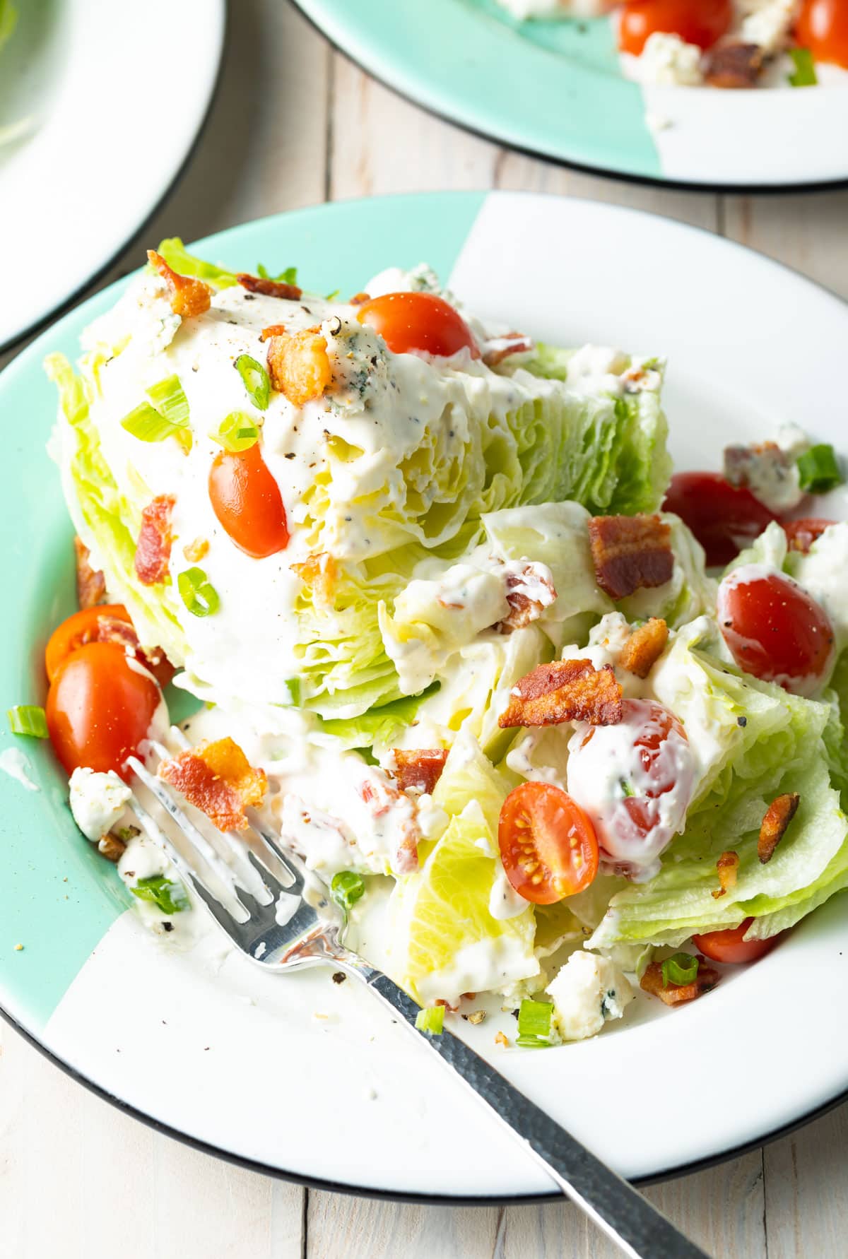 Wedge salad with iceberg lettuce cut into two portions on a plate.