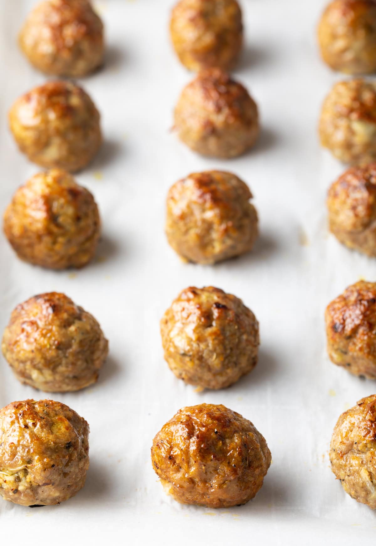 Cooked turkey meatballs lined up on a baking sheet