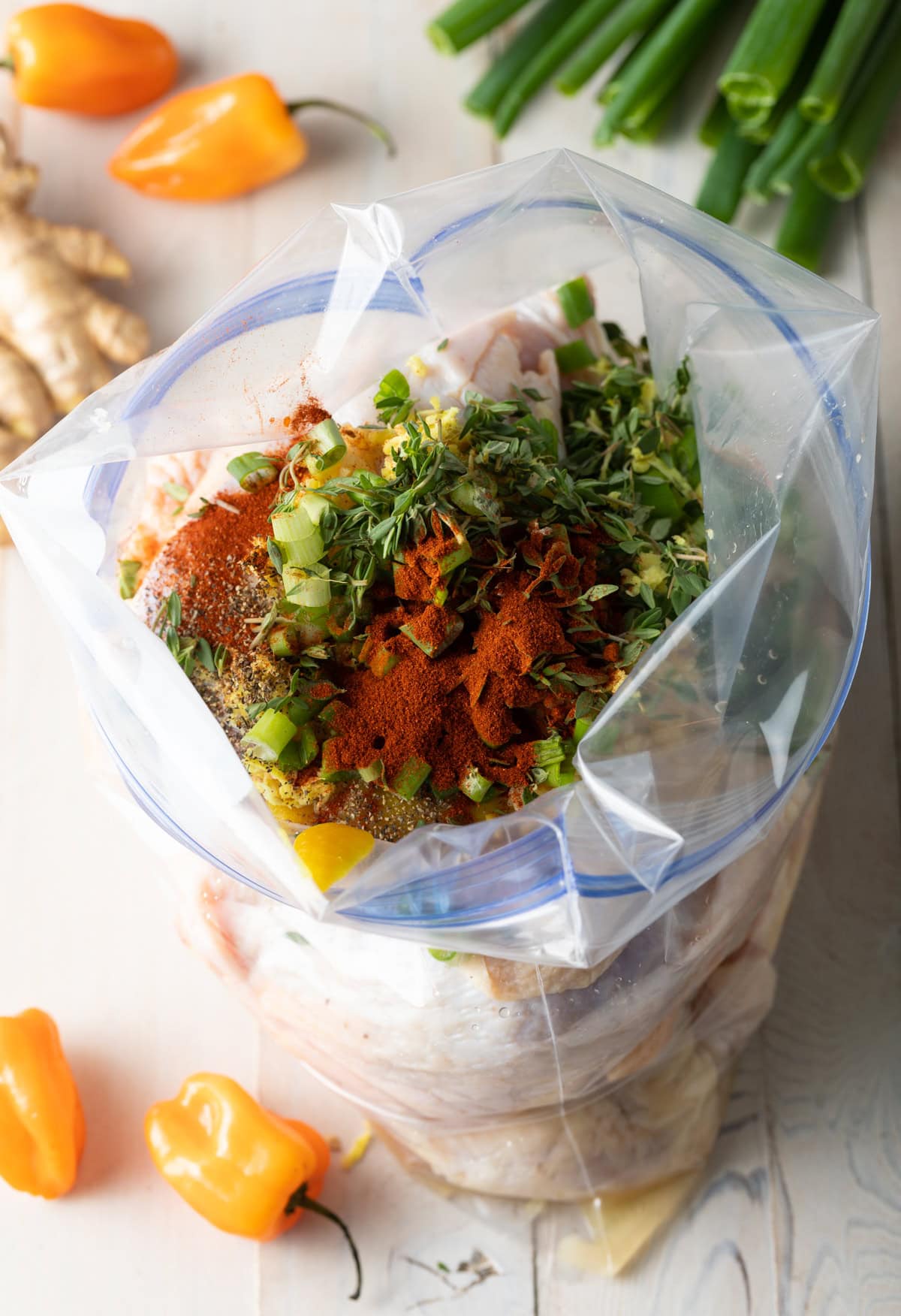 Zip loc bag filled with ingredients for marinade and pieces of raw chicken.