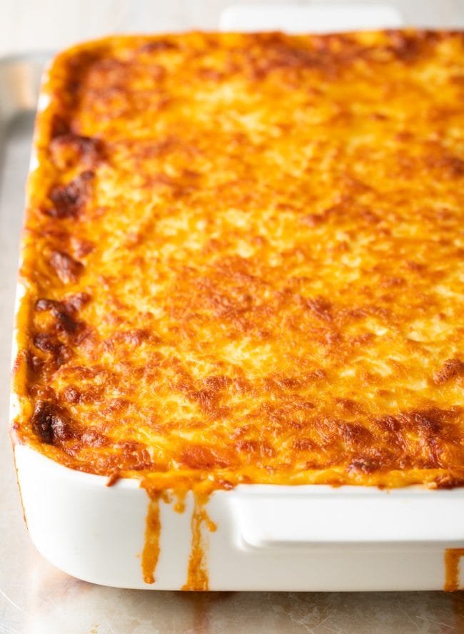 Close view of cheesy pasitsio in a white baking dish.