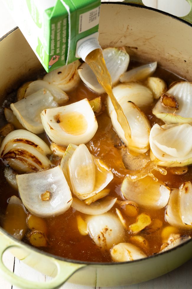 veggie broth with onions and mushrooms in a giant sauce pot on the stove 
