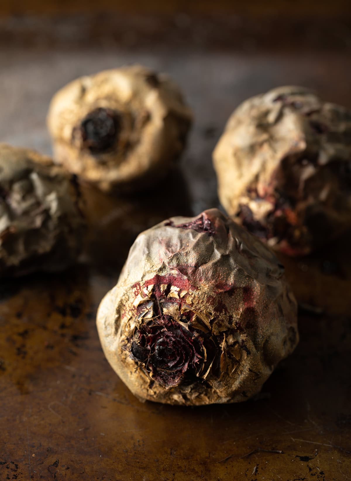 Closeup of baked unpeeled beets on a cooking tray.