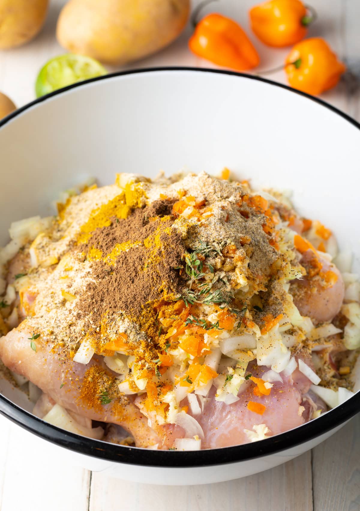 Chicken marinading in bowl with spices.