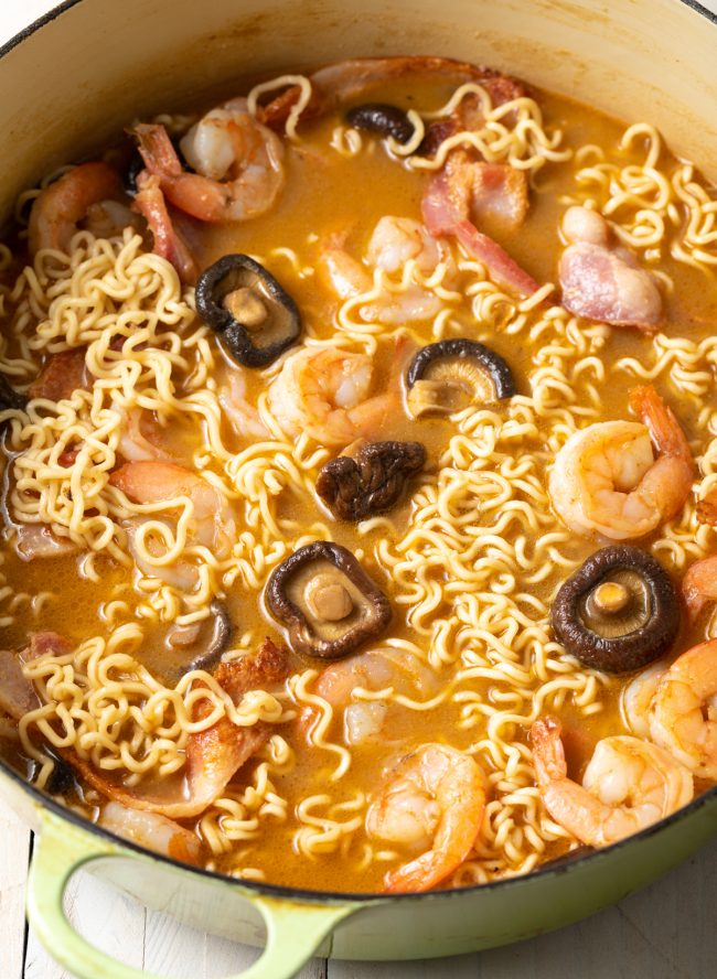 shrimp and ramen noodles with mushrooms and bacon in a stockpot